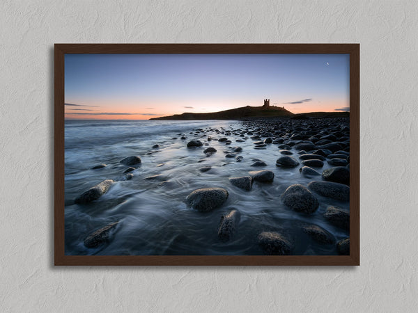 Ethereal Dawn coastal wall art featuring Northumbrian castle ruins, rocky shoreline and calm sea at sunrise