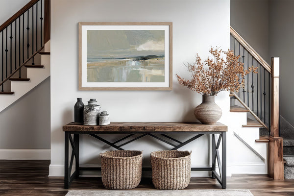 Pale Estuary in a light wood frame above a console table between two staircases.