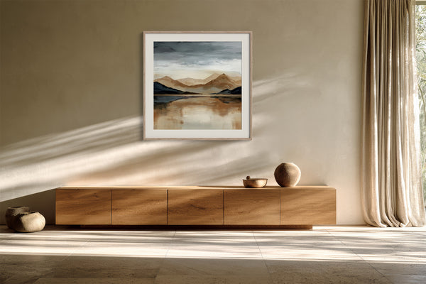 White-framed mountain lake artwork hung above a floating wood sideboard.