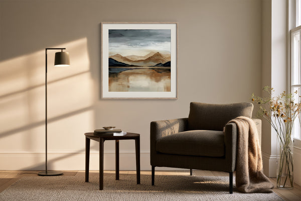 White-framed mountain lake artwork above an upholstered armchair, side table, and floor lamp.
