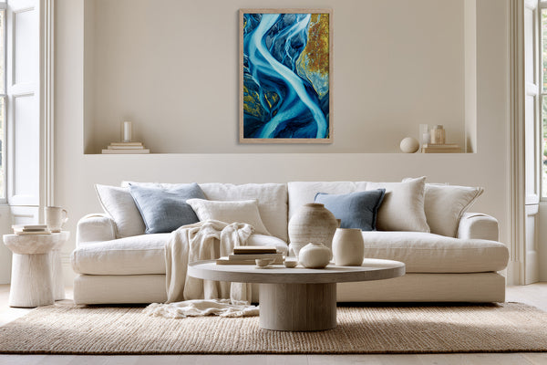 Framed blue glacial river artwork displayed above a white sofa with pale blue cushions.