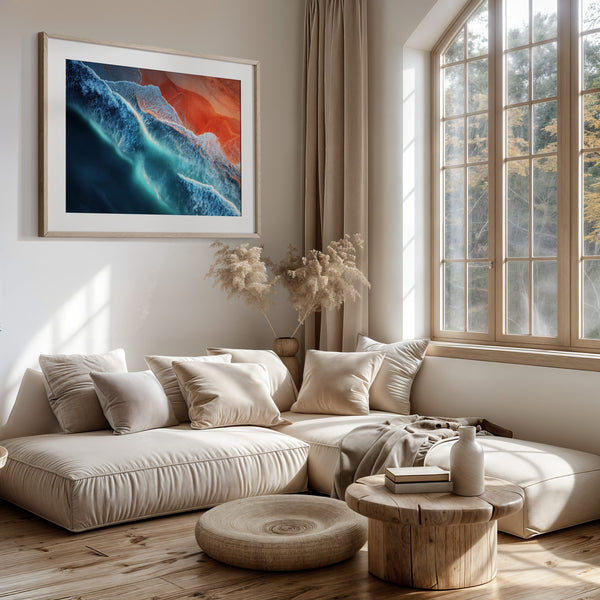 Ember Tide print in a light wood frame above a cream sectional beside tall windows.