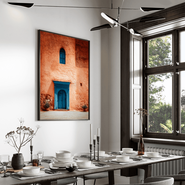 Framed Moroccan street scene art print featuring a vivid blue doorway and ochre wall. A soulful, timeless piece for eclectic interiors.