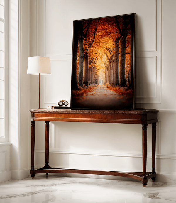 Framed wall art of a tree-lined autumn path beneath golden leaves. A nostalgic woodland print in warm light. Ready to hang.