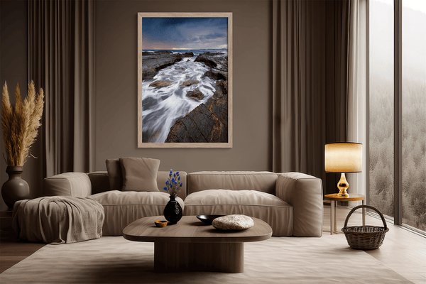 Framed wall art of the Australian coast with rugged rocks, azure sea, and moody skies. A striking coastal landscape print. Ready to hang.