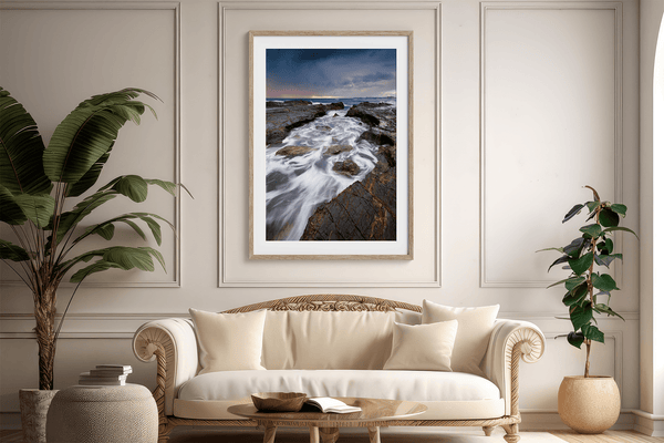 Framed wall art of the Australian coast with rugged rocks, azure sea, and moody skies. A striking coastal landscape print. Ready to hang.