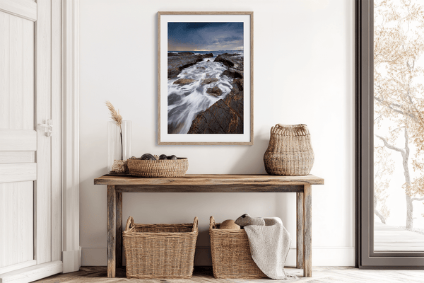 Framed wall art of the Australian coast with rugged rocks, azure sea, and moody skies. A striking coastal landscape print. Ready to hang.