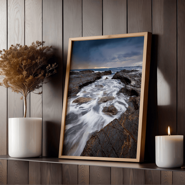 Framed wall art of the Australian coast with rugged rocks, azure sea, and moody skies. A striking coastal landscape print. Ready to hang.