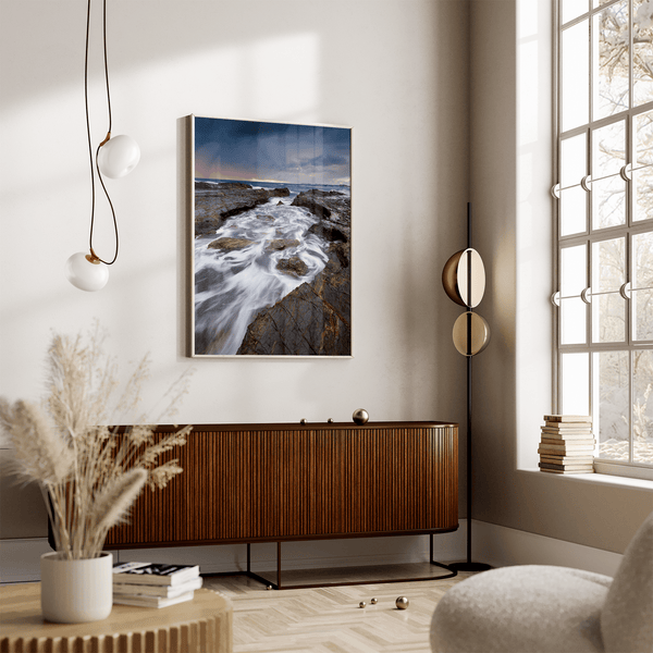 Framed wall art of the Australian coast with rugged rocks, azure sea, and moody skies. A striking coastal landscape print. Ready to hang.