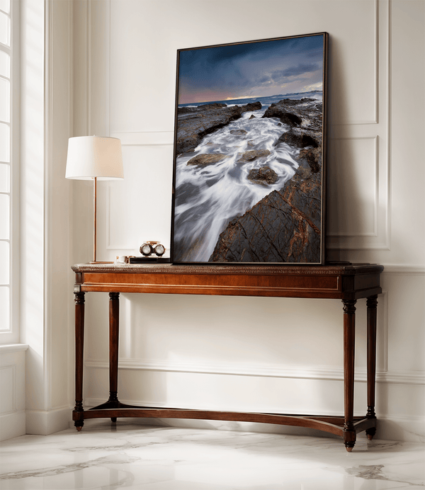 Framed wall art of the Australian coast with rugged rocks, azure sea, and moody skies. A striking coastal landscape print. Ready to hang.