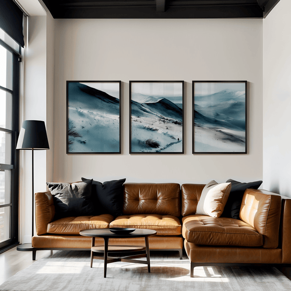 Serenity's Peaks watercolor triptych wall art above a brown leather sofa.