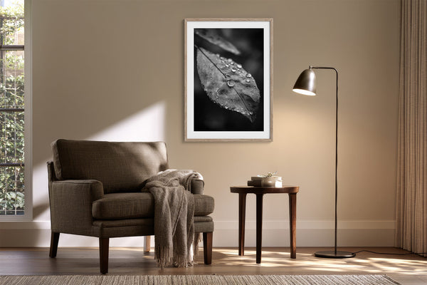 Light-framed dew-covered leaf wall art above an armchair and side table with a floor lamp.