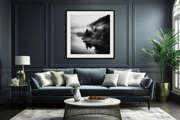 Black-framed Mistwater Valley print above a dark blue sofa with pale cushions.