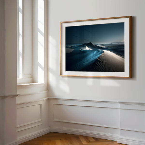 Close view of matted desert dune artwork in a light wood frame on a white paneled wall.