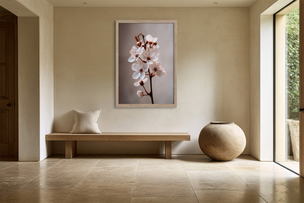 Light wood-framed cherry blossom print above a wooden bench beside a large ceramic vessel.