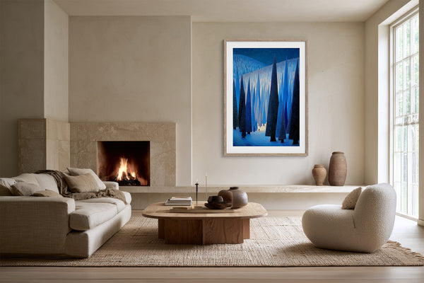 White-framed forest print displayed between a fireplace and tall window in a living room.