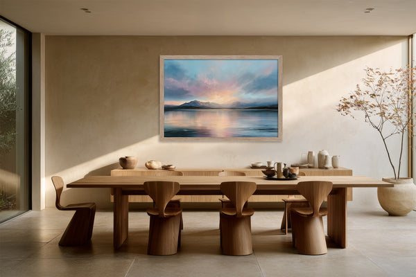 Light wood-framed mountain lake artwork above a long wooden dining table.