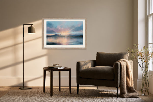Light wood-framed mountain lake artwork above an armchair, side table, and floor lamp.