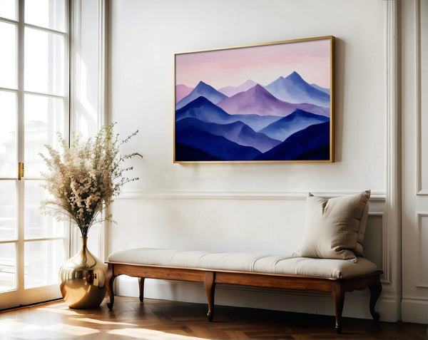 Violet Ranges mountain artwork in a gold-toned frame above a wooden bench and vase.