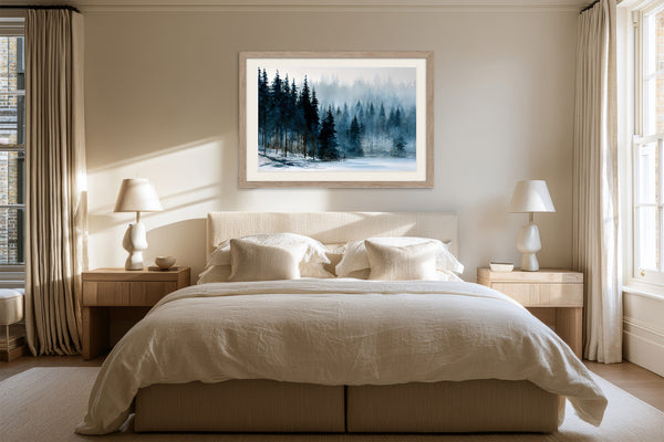 Framed snowy pine forest artwork centered above a bed with cream linens.