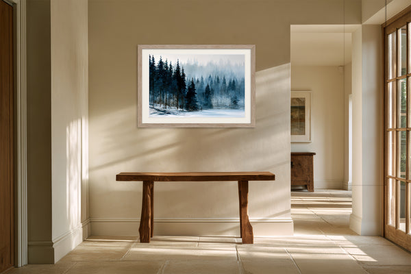 Framed snowy pine forest artwork above a rustic wooden console in a sunlit hallway.