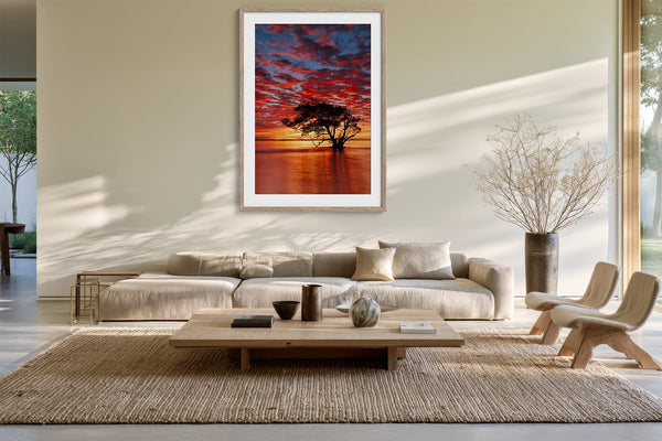 Light wood-framed sunset tree print displayed above a cream sofa and low coffee table.