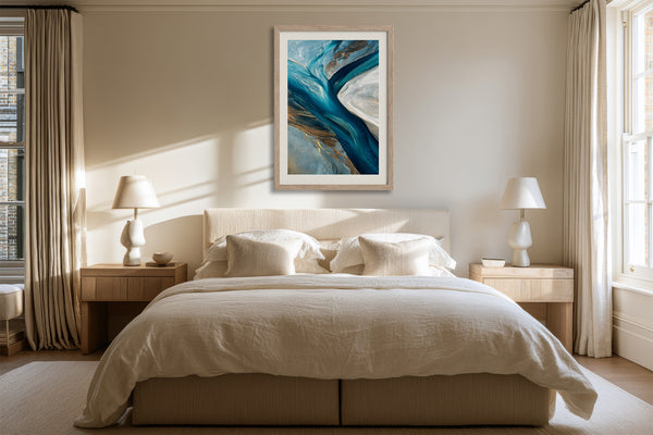 Framed teal, navy, grey and gold abstract artwork above a bed between two bedside lamps.