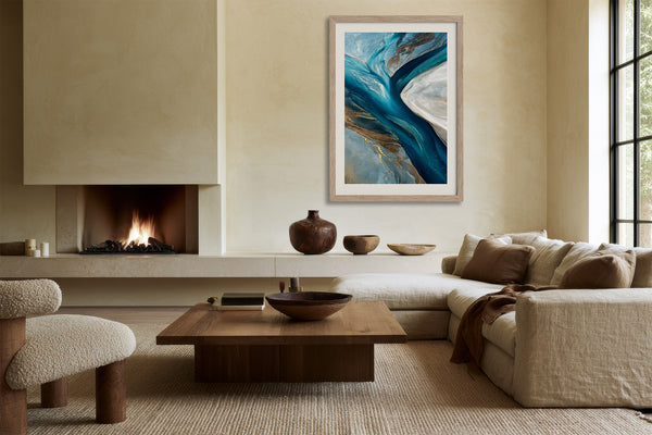 Framed blue and grey abstract artwork displayed above a low sofa beside a lit fireplace.