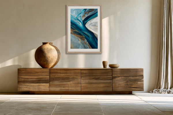 Framed blue abstract artwork above a long wooden sideboard with ceramic vessels.