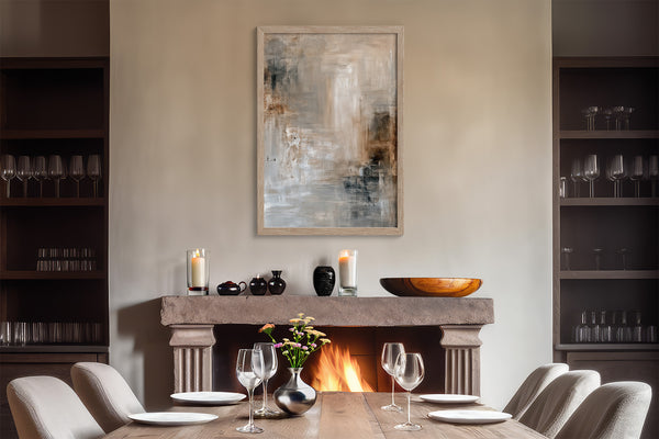 Framed textured abstract artwork above a fireplace set for dining with wine glasses.