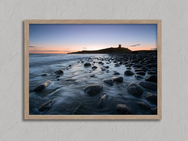Ethereal Dawn coastal wall art featuring Northumbrian castle ruins, rocky shoreline and calm sea at sunrise