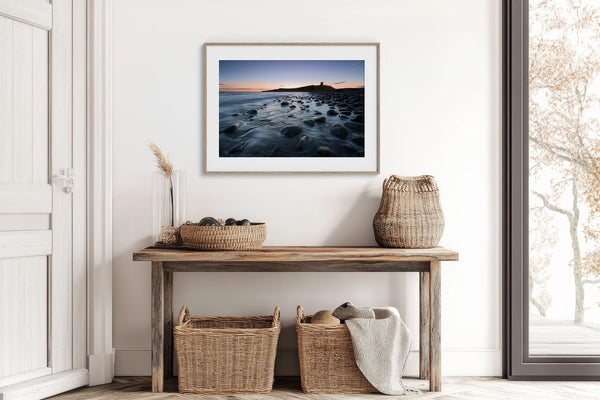 Ethereal Dawn coastal wall art featuring Northumbrian castle ruins, rocky shoreline and calm sea at sunrise