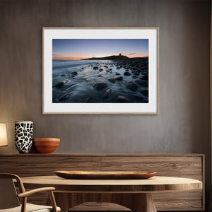 Ethereal Dawn coastal wall art featuring Northumbrian castle ruins, rocky shoreline and calm sea at sunrise