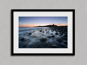 Ethereal Dawn coastal wall art featuring Northumbrian castle ruins, rocky shoreline and calm sea at sunrise