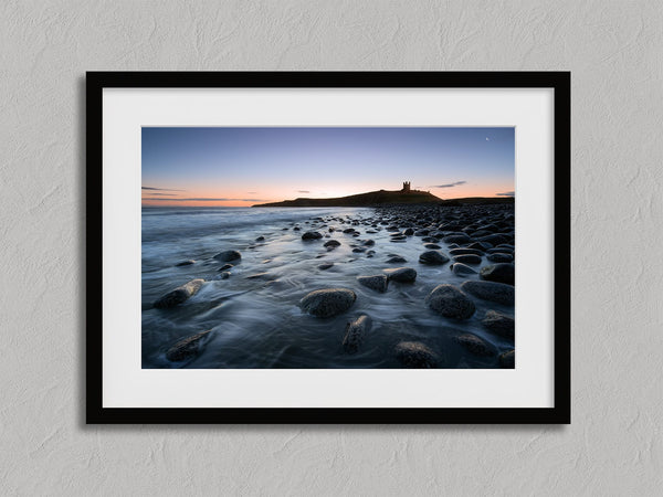 Ethereal Dawn coastal wall art featuring Northumbrian castle ruins, rocky shoreline and calm sea at sunrise