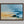 Abstract coastal artwork with layered blue waves, textured ivory forms and a warm golden shoreline.