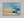 Abstract coastal artwork with layered blue waves, textured ivory forms and a warm golden shoreline.