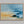 Abstract coastal artwork with layered blue waves, textured ivory forms and a warm golden shoreline.