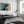 Aerial coastal view of deep teal water curling into pale sand along a sweeping shoreline.