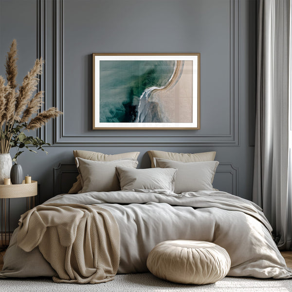 Aerial coastal view of deep teal water curling into pale sand along a sweeping shoreline.