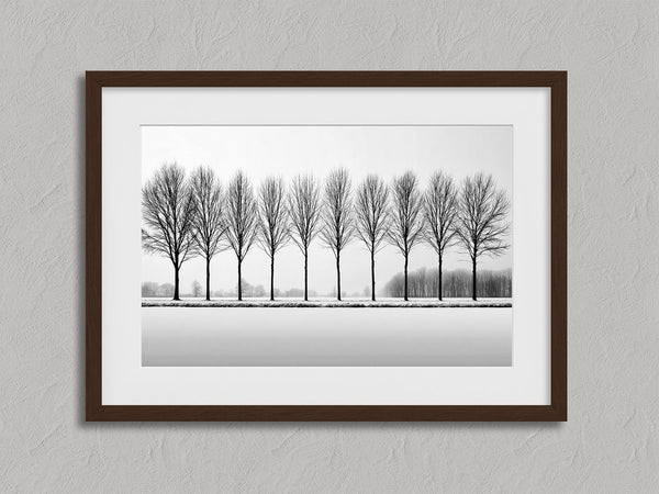 Black and white tree wall art featuring a row of bare winter trees across a minimalist snowy landscape