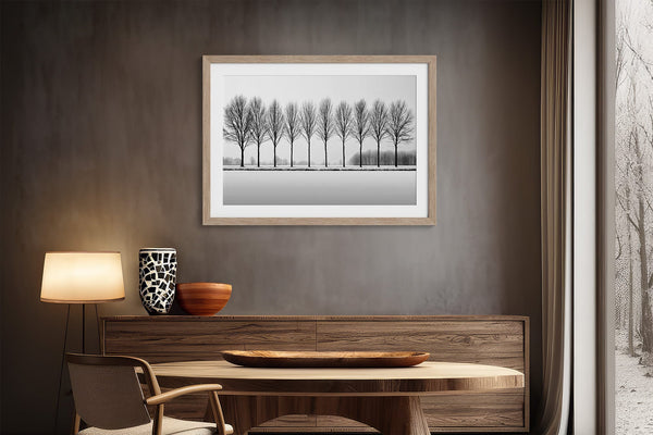 Black and white tree wall art featuring a row of bare winter trees across a minimalist snowy landscape