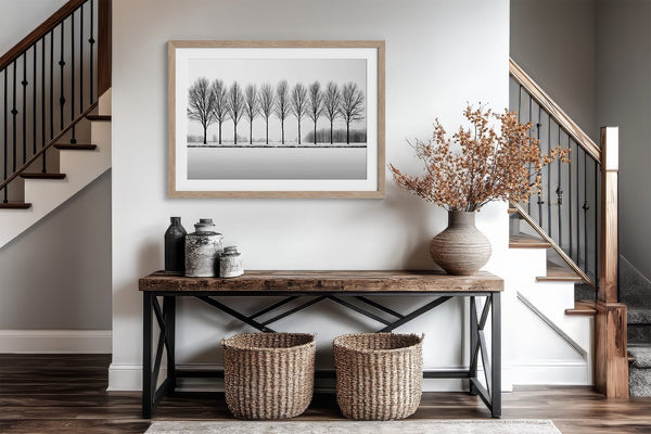 Black and white tree wall art featuring a row of bare winter trees across a minimalist snowy landscape