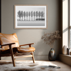 Black and white tree wall art featuring a row of bare winter trees across a minimalist snowy landscape