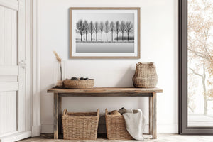 Black and white tree wall art featuring a row of bare winter trees across a minimalist snowy landscape