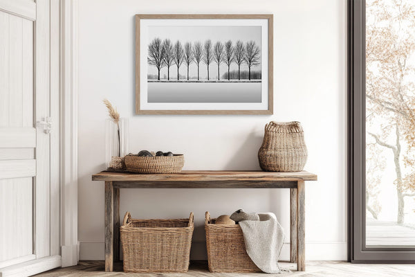 Black and white tree wall art featuring a row of bare winter trees across a minimalist snowy landscape