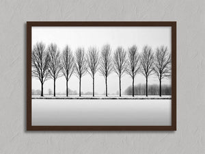 Black and white tree wall art featuring a row of bare winter trees across a minimalist snowy landscape