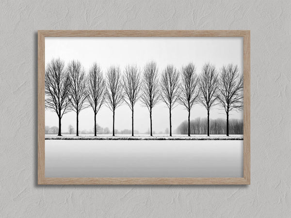 Black and white tree wall art featuring a row of bare winter trees across a minimalist snowy landscape