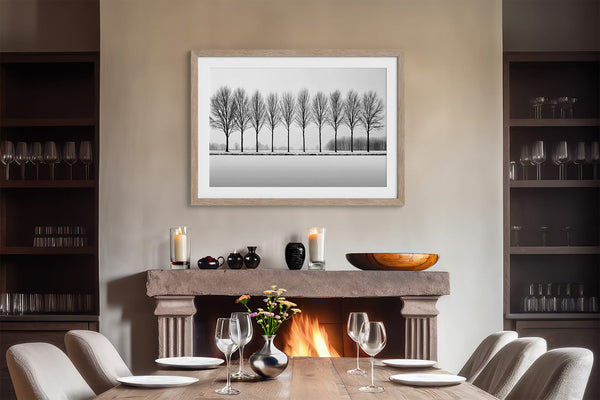 Black and white tree wall art featuring a row of bare winter trees across a minimalist snowy landscape