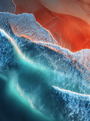 Aerial view of a red sand dune with blue ocean waves crashing against it. www.AtelierLumin.art. 